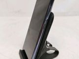 the back of a black cell phone on a stand with a white background