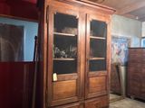 a tall wooden cabinet with glass doors in a room