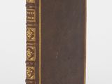 un vieux livre à la couverture brune et à la bordure dorée