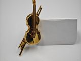 a close up of a gold violin pin on a white surface