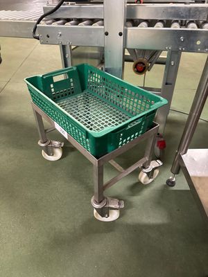 un panier vert posé sur un chariot métallique dans une usine
