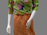 an image of a mannequin wearing a green and orange top and orange skirt