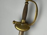 a gold colored sword with a black handle on a white background