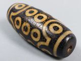 a close up of a black and gold bead on a white surface