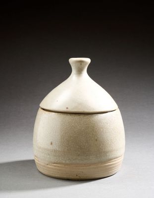un vase blanc muni d'un couvercle, posé sur une table