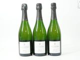 trois bouteilles de vin posées les unes à côté des autres sur une surface blanche