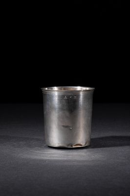 an old silver cup sitting on a table with a black background