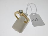 a white tag and a gold ring on a white table