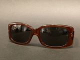 sunglasses on a table with a reflection of a person in the lens