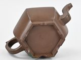 a brown teapot with a handle on a white surface
