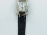 une photo d'une montre posée sur une surface blanche, avec un bracelet noir