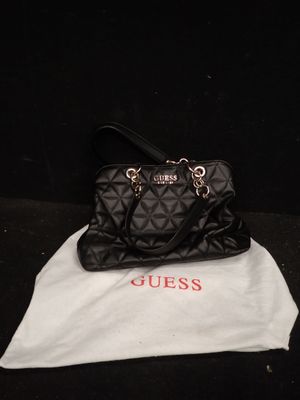 un sac à main noir matelassé posé sur un sac blanc, sur un fond noir