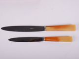 two knives are sitting next to each other on a white surface