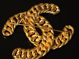 a close up of a gold brooch on a black surface