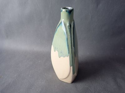 a green and white vase sitting on a gray surface