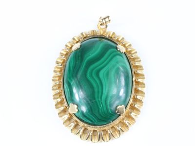 un gros plan d'un pendentif vert et doré sur fond blanc