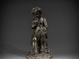 a bronze statue of a woman sitting on a rock