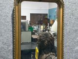 a mirror hanging on the wall with a statue in front of it