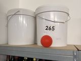 several buckets of wine sit on a shelf in a room