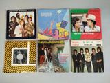 Six albums vintage des Rolling Stones, dont *The Rolling Stones*, sont posés sur une table