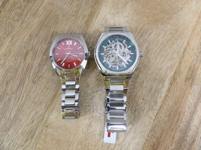 two watches sitting on a wooden table next to each other