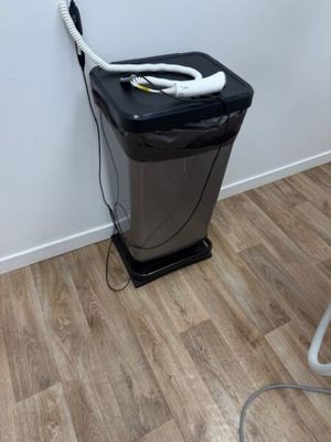 une image représentant une poubelle en noir et blanc à laquelle est raccordé un tuyau