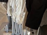 beaucoup de vêtements suspendus au mur, à côté d'une poubelle