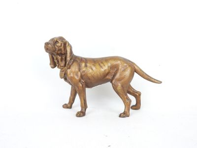 statue en bronze représentant un chien posée sur une surface blanche, avec un fond blanc