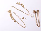 trois bijoux en or posés sur une surface blanche