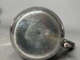 a silver pocket watch sitting on a table next to a pair of scissors