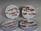 quatre assiettes ornées de poissons, posées sur une table