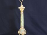 a green and gold lamp with a glass shade on top of it
