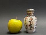 an apple next to a salt shaker on a table