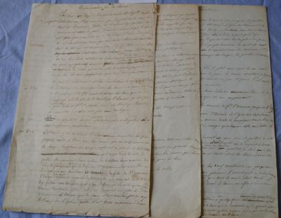 two pages of old paper with writing on them sitting on a table