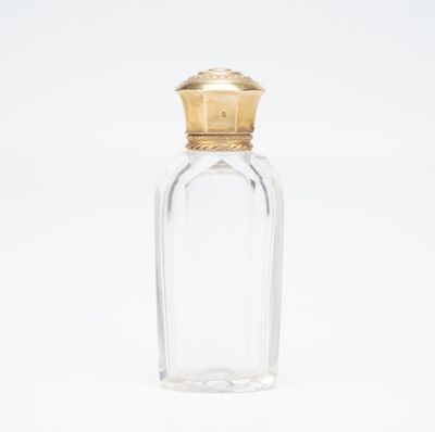 une bouteille en verre transparent avec un bouchon doré, sur fond blanc