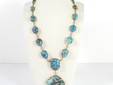 un collier avec un pendentif en pierre bleue et verte sur un mannequin