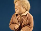 a small doll that is wearing a brown coat