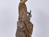 bronze statue of a woman sitting on a rock with a bird in her hand