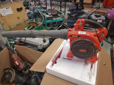 a red blower sitting on top of a cardboard box