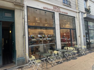 many tables and chairs outside of a store on the sidewalk