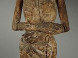 wooden statue of a woman holding her hands on her chest