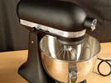 a black mixer on a wooden table with a black background