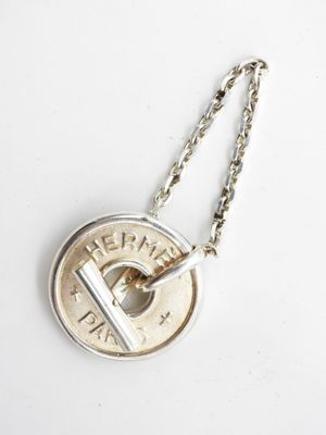 a close up of a coin on a chain on a white surface