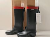 pair of black rain boots with red trims on a white surface