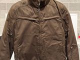 une veste marron suspendue à un cintre dans un magasin, avec une étiquette de prix