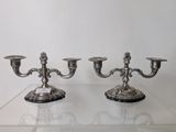 pair of antique silver plated candelabs on display in a glass case