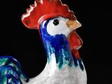 a ceramic rooster figurine with a red and blue head