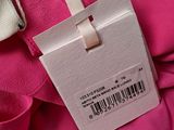 the label on a pink dress is attached to a white tag