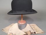 un chapeau noir posé sur un pied de mannequin et une paire de gants en cuir
