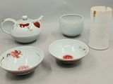 four bowls, a teapot, and a vase on a table